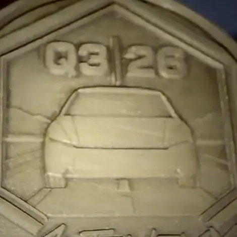 Close-up of a raised car relief inside a hexagon frame on a coin