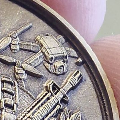 Close-up of the Desperado coin edge: matte, blackened textured background between raised drones, inside a raised polished rim