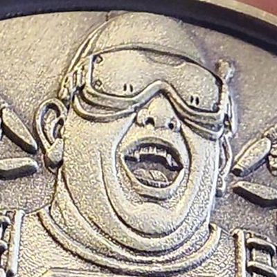 Close-up of the Desperado UAS Platoon coin: the face and goggles are sculpted and stand above the background, with polished high points