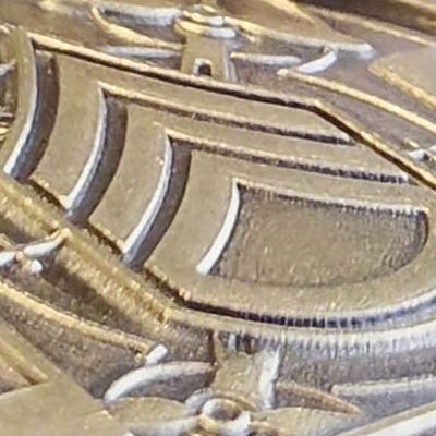KRF17 coin seen at an angle: the sergeant chevrons rise in stepped layers, each one a different height